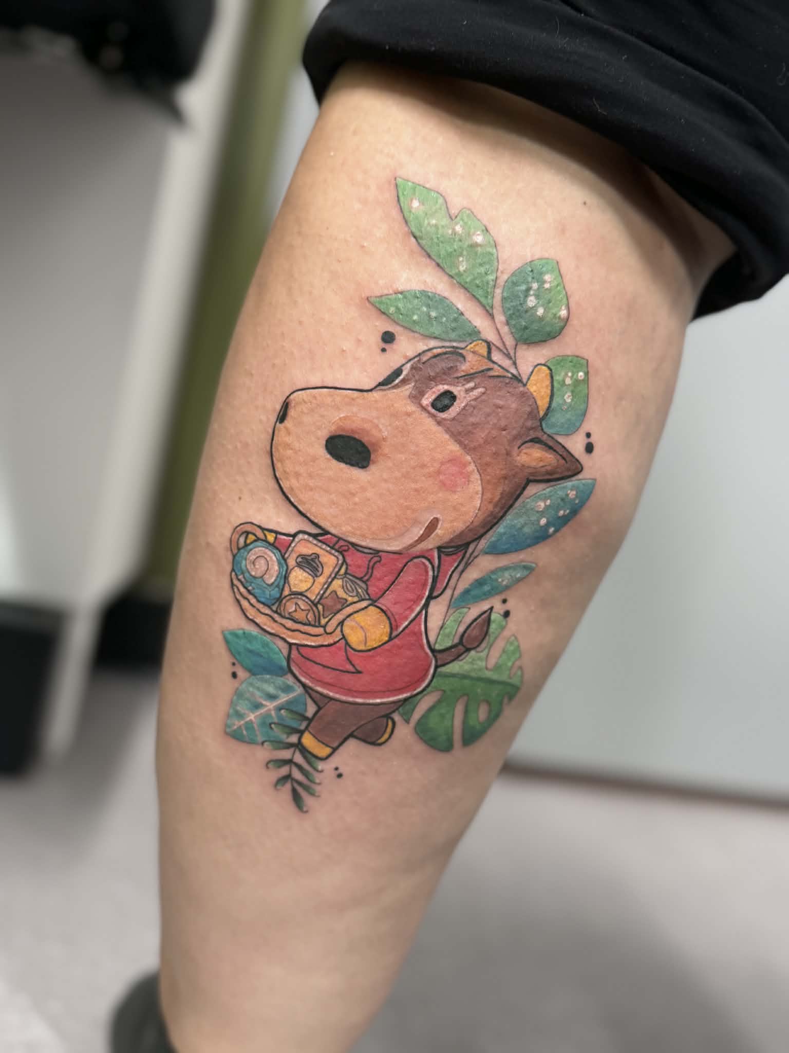 Vibrant Animal Crossing illustrative tattoo featuring a custom character with a gift basket, expertly executed with soft color saturation by AJ at Poking Hazard in Edmonton, AB.