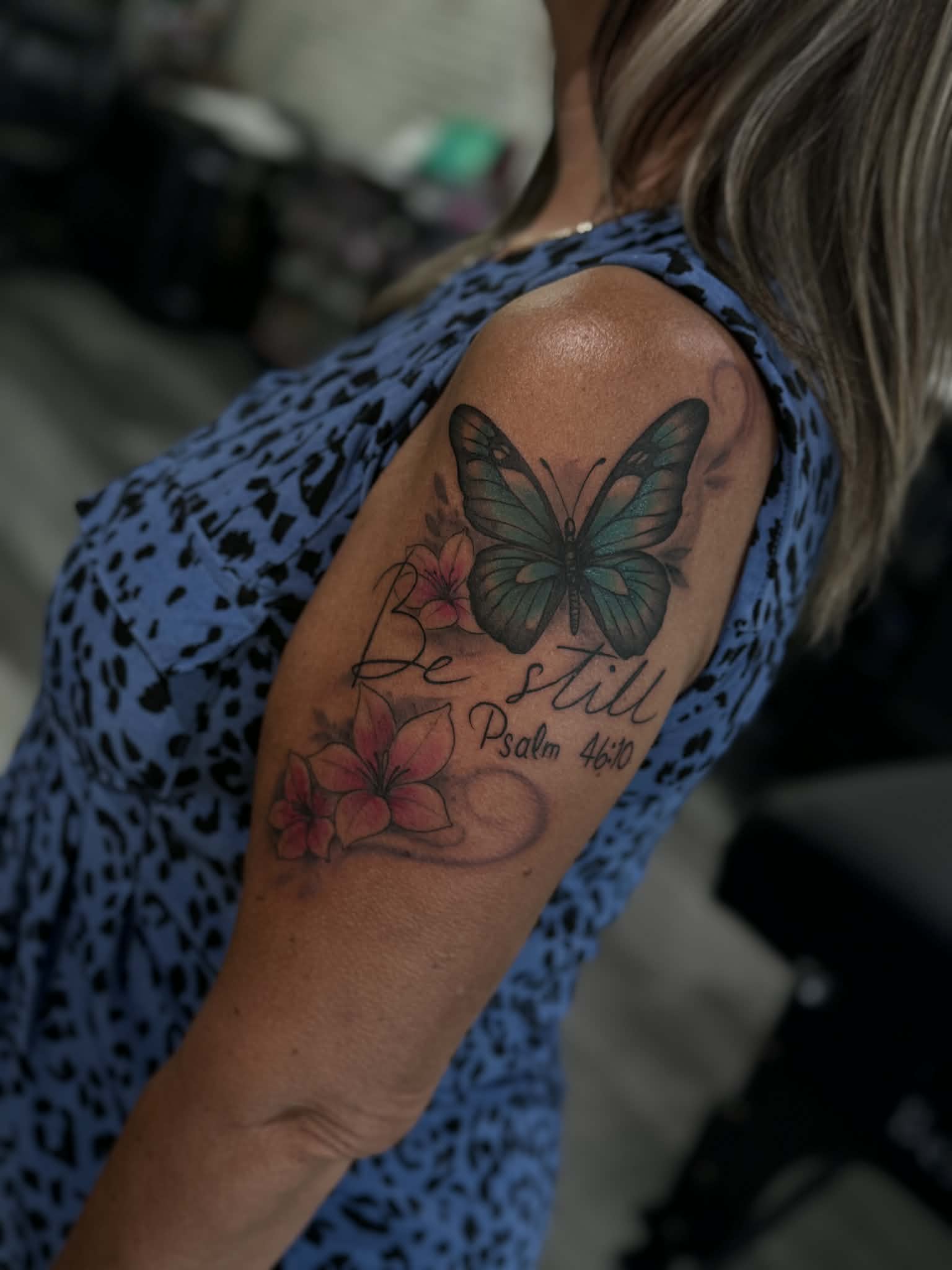 Vibrant butterfly and floral tattoo with custom 'Be Still' scripture script, expertly tattooed by AJ at Poking Hazard’s private, inclusive studio in Edmonton, AB
